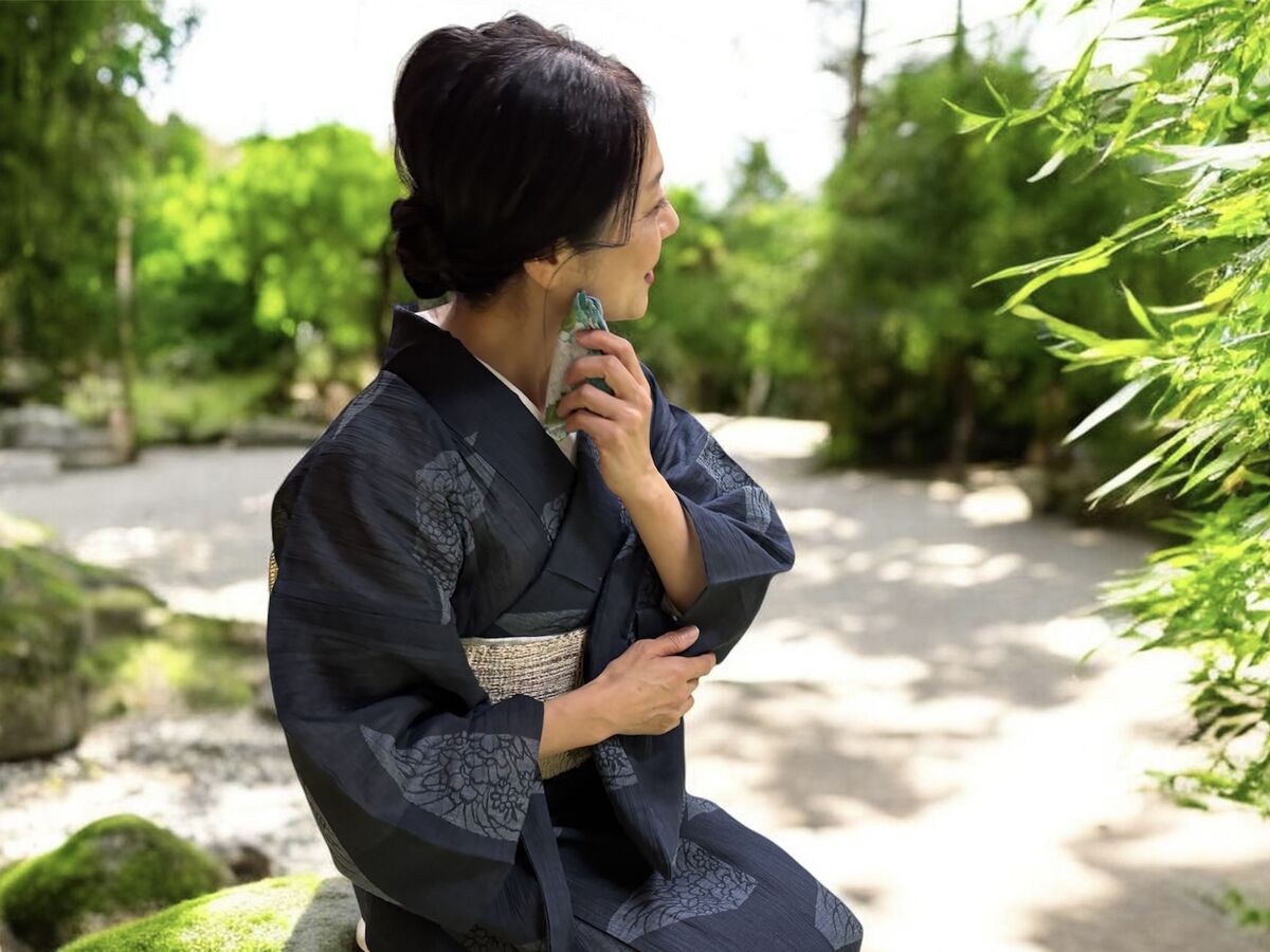 木もれ日の下、着物姿で額の汗をそっと拭う所作