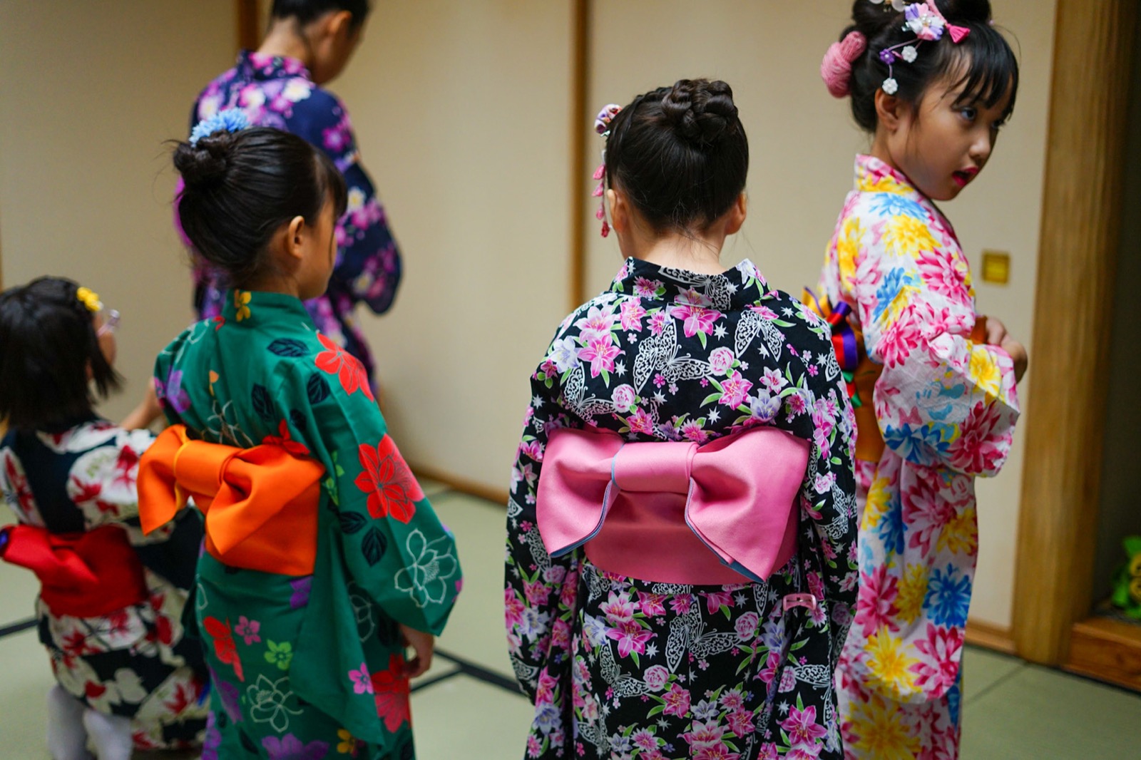 色とりどりの花結びの帯を結んだ子どもたちの後ろ姿