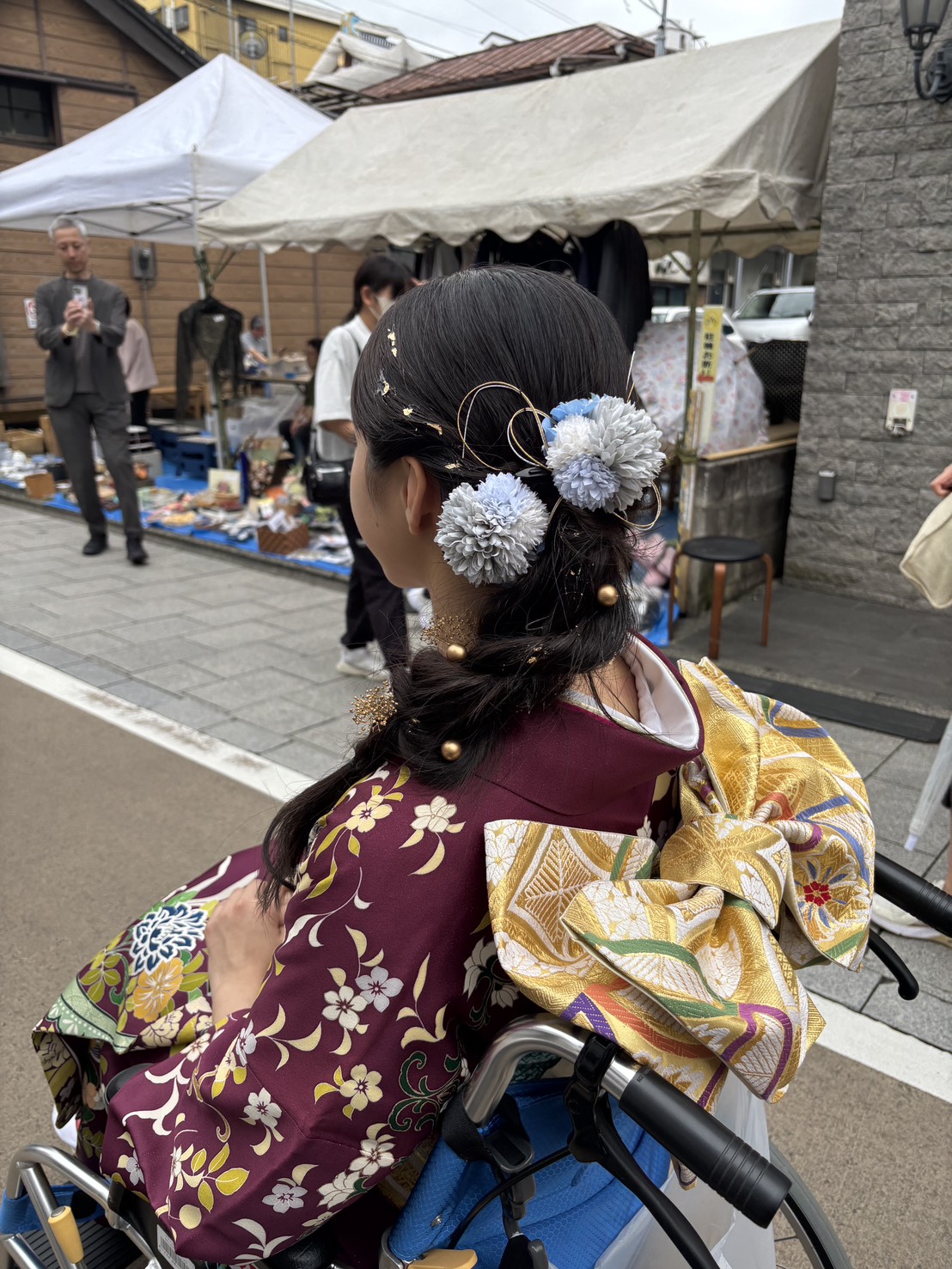 金の袋帯に花結びをあしらった、車椅子の振袖姿の後ろ姿