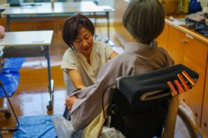 笑顔で優しく、車いすの方に着物の着付けを行う西山智香先生